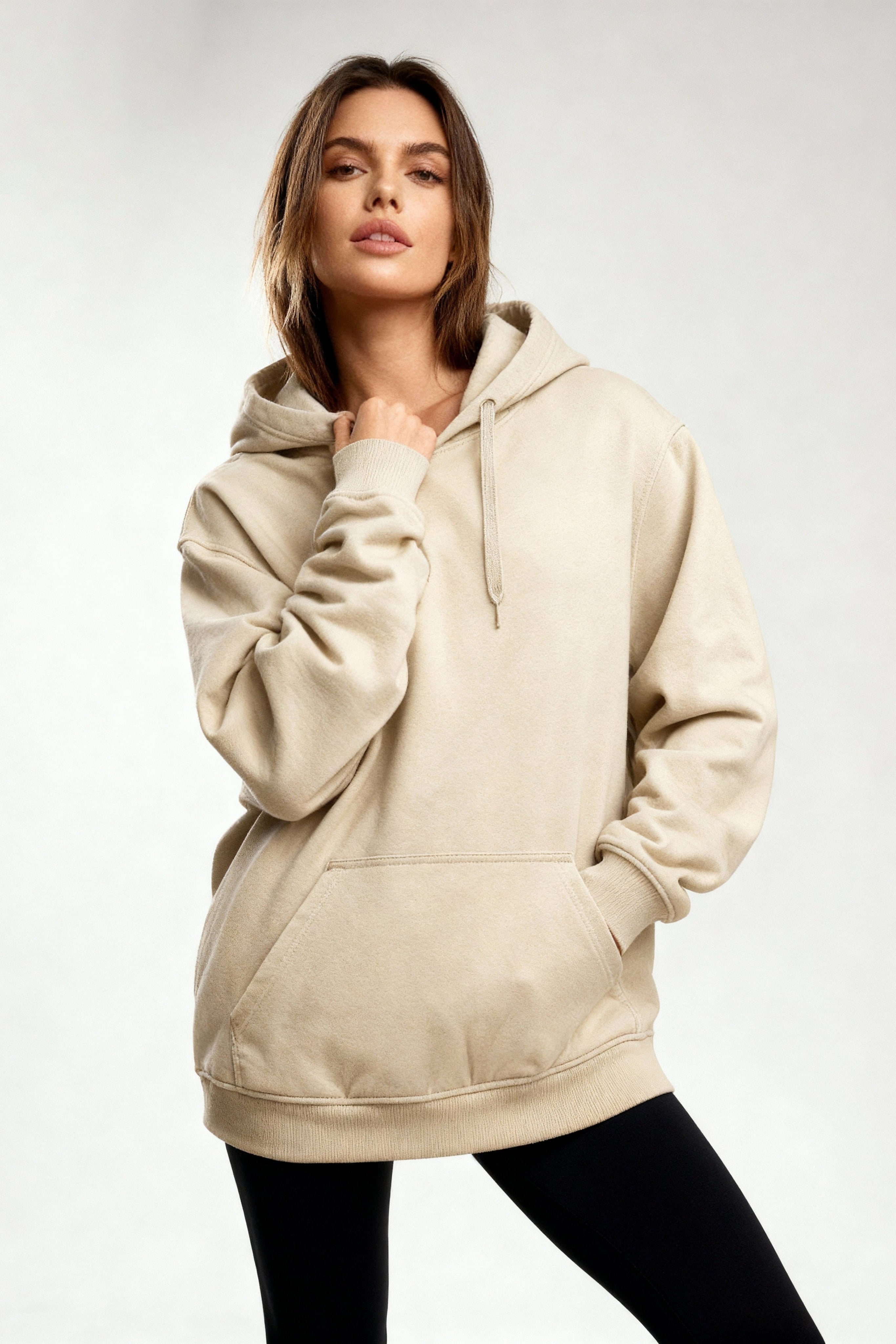 Woman wearing a beige hoodie on a plain background